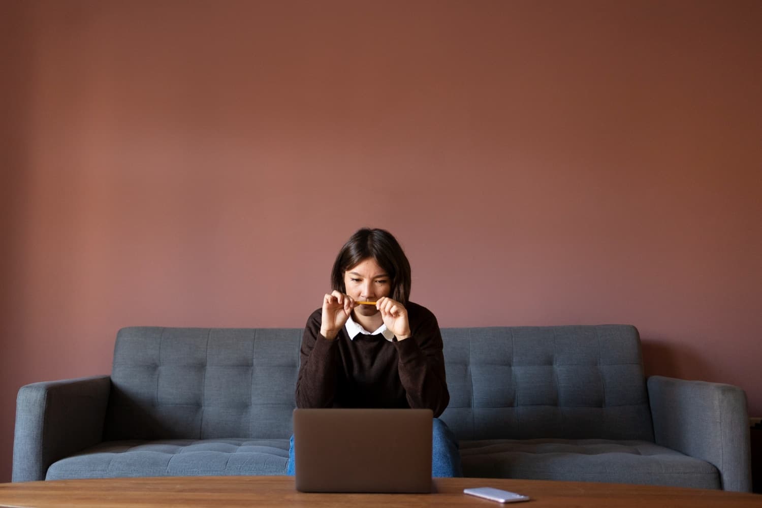 A person sitting in a couch in front of the laptop and feeling the fear of starting counselling in Australia.