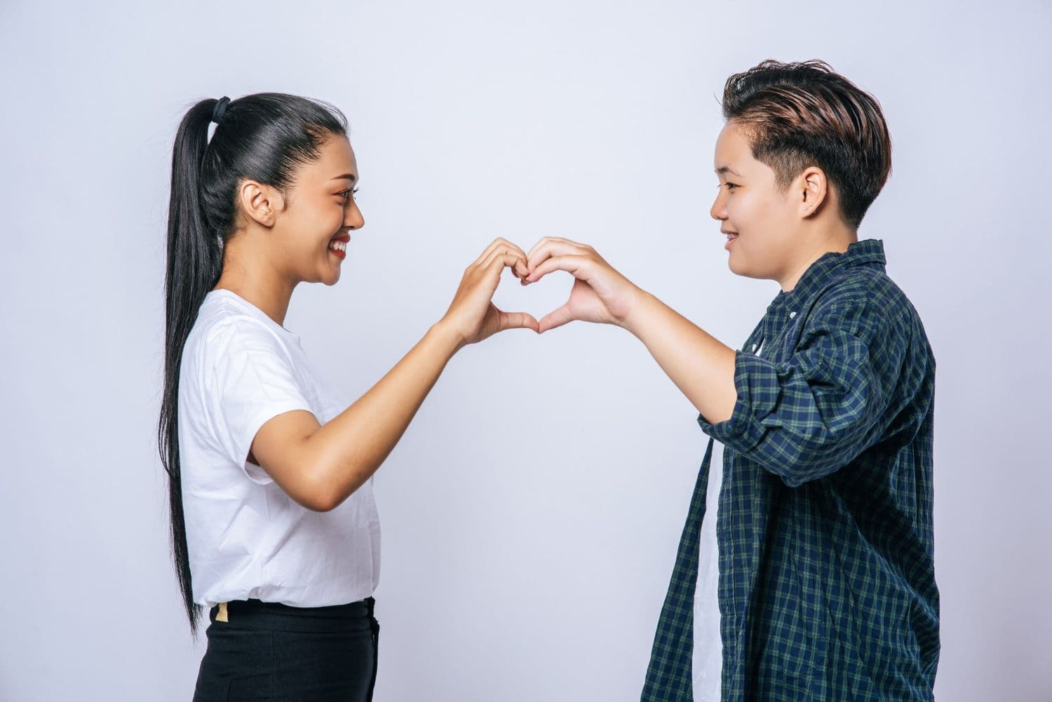 Two women holding their hands in a heart shape symbolising true love.