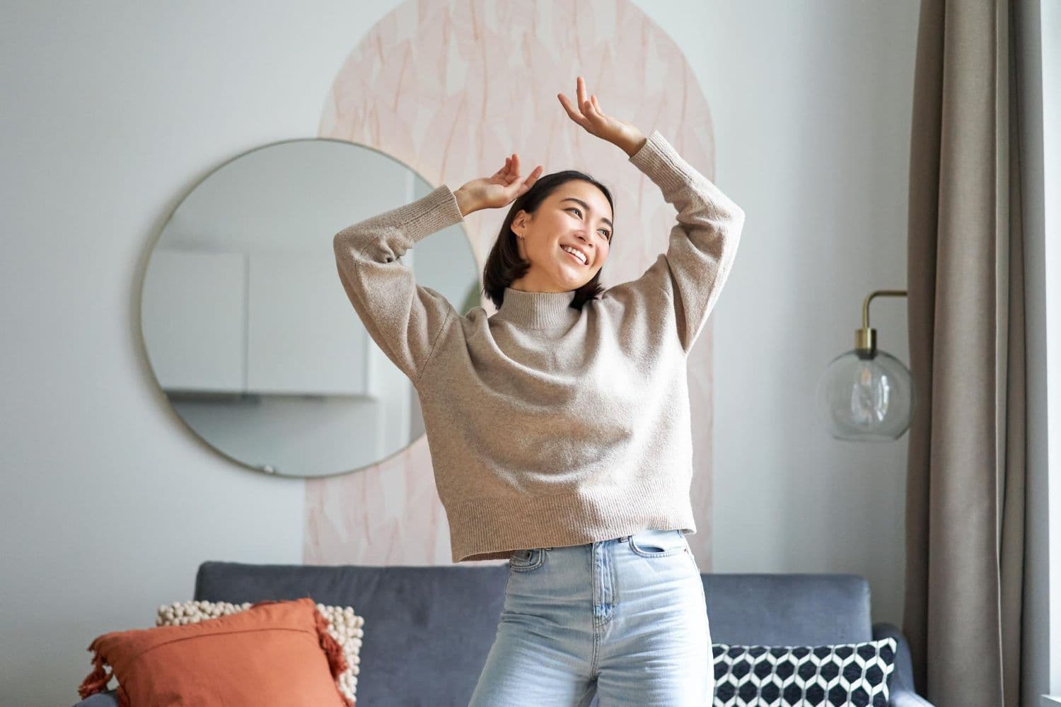 A person smiling wide with arms raised after reading a couple of happiness quotes.