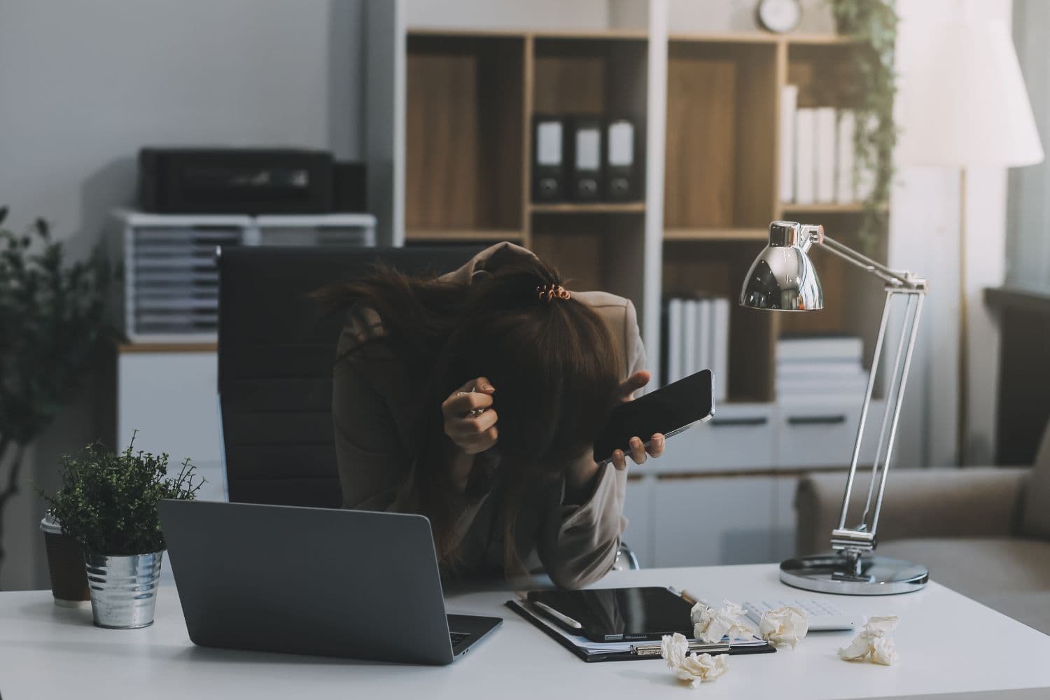 A person looking upset sitting at the work desk due to burnout and workplace stress.