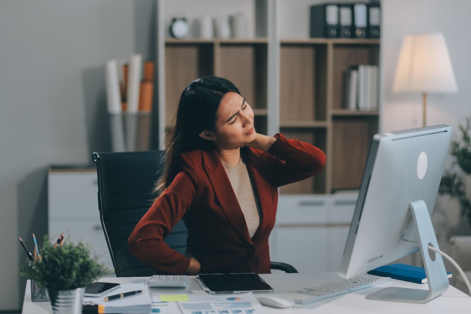 A person in the office has aches and pains in her torso due to burnout and work stress.