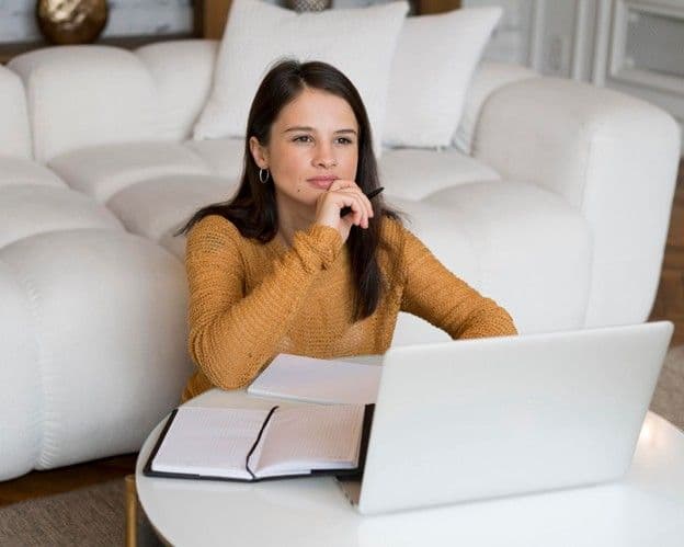 A person seated before a laptop, ready for an online counselling session, thinking deeply about something.