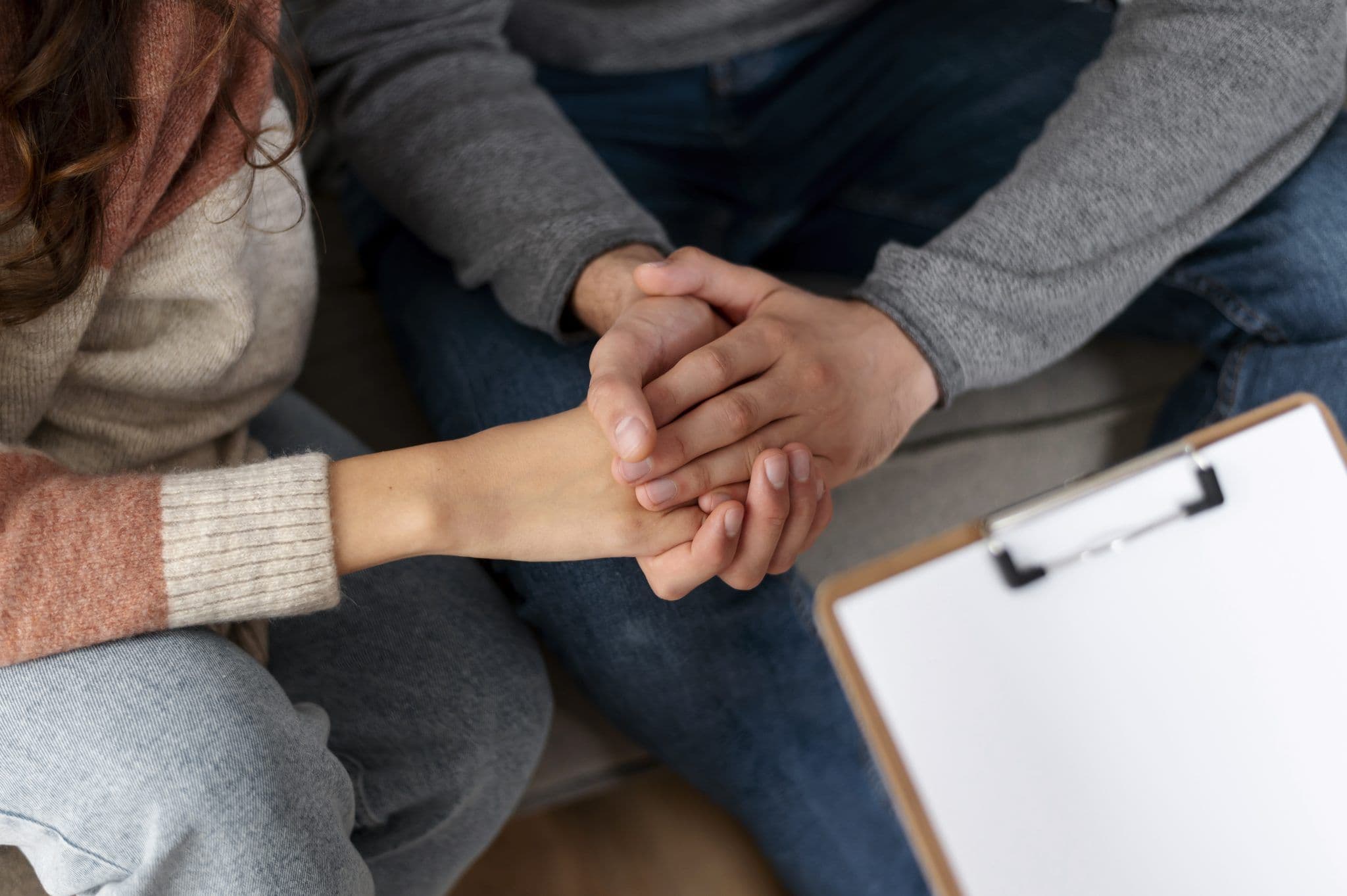 Two people holding hands in mutual support during mental health counselling in Singapore.