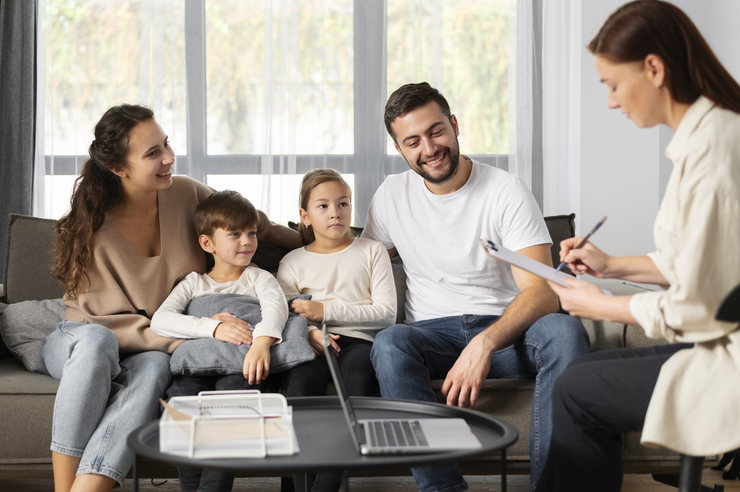 A family of four smiles and interacts with a therapist, capturing a moment in a therapy session, reflecting an aspect of what therapy is.