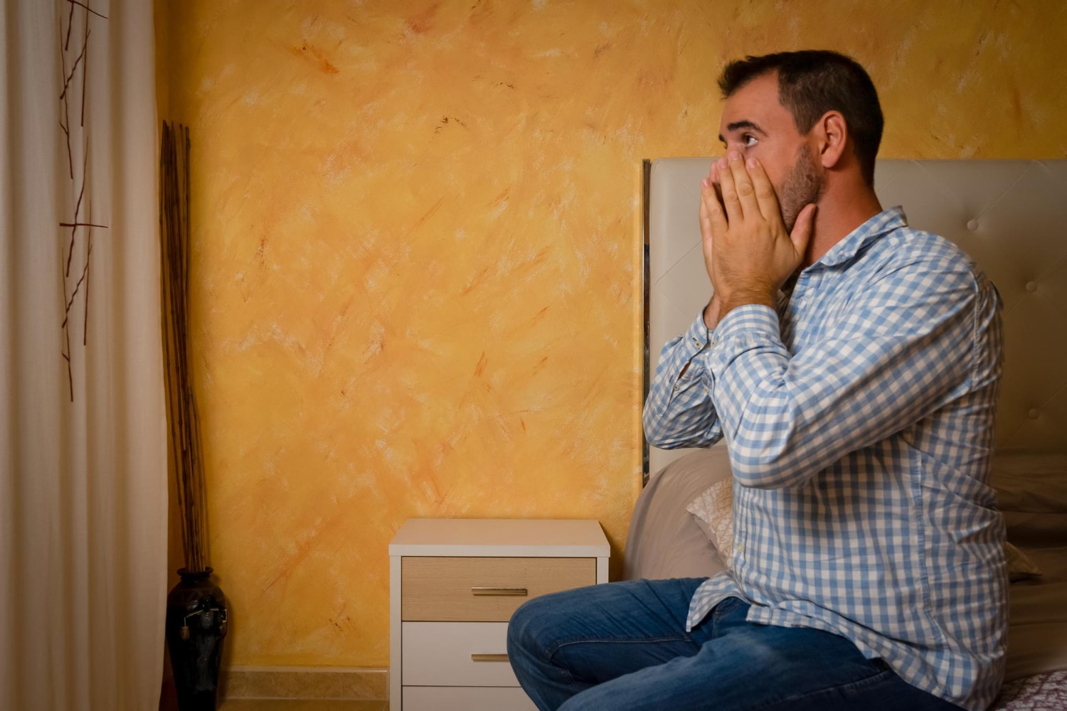 A man sitting in the couch with hands on face and worrying about starting counselling in Australia.
