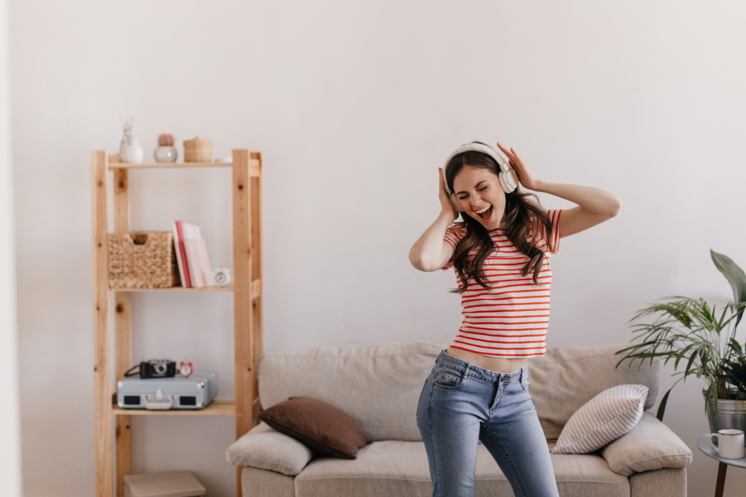 A person feeling happy and dancing with headphones on after seeking the help of an affordable therapist in Malaysia.