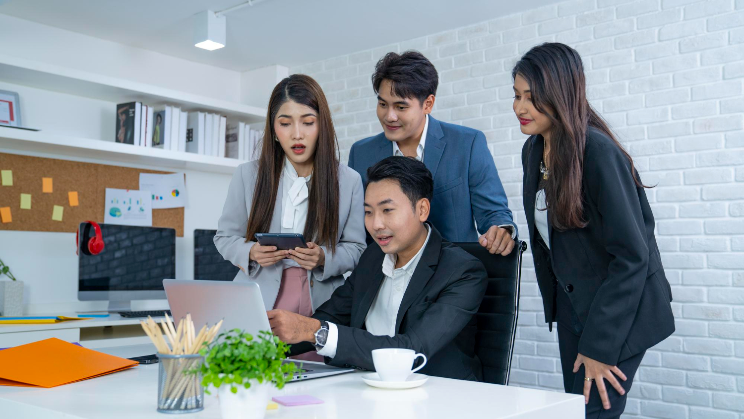 4 employees looking at the laptop and exploring options to engage with therapy services in Singapore.
