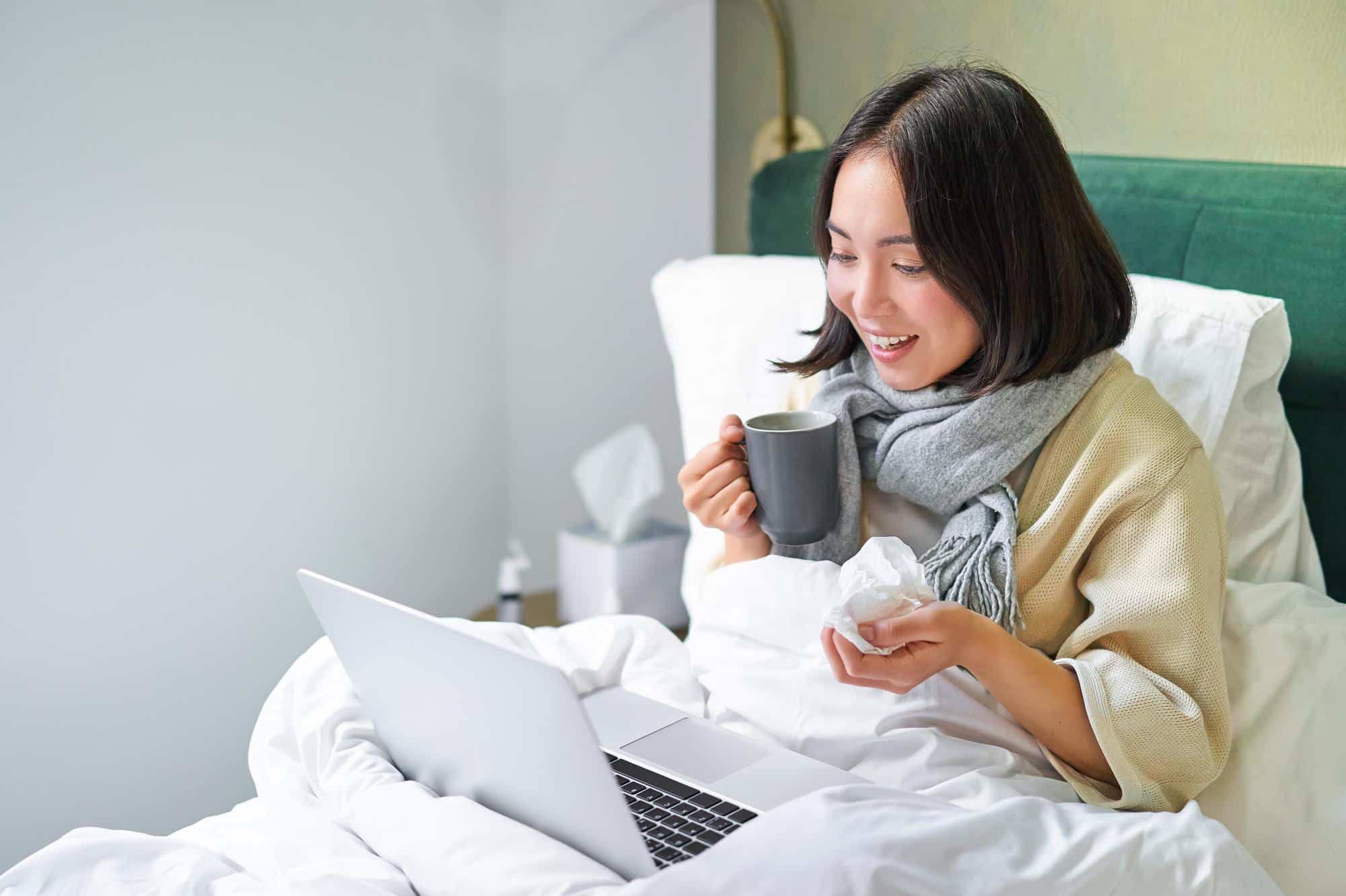 A person attending an online therapy session from the comfort of their bed.